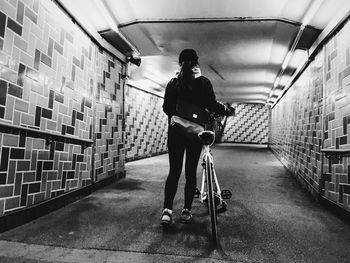 Rear view of woman standing in illuminated tunnel