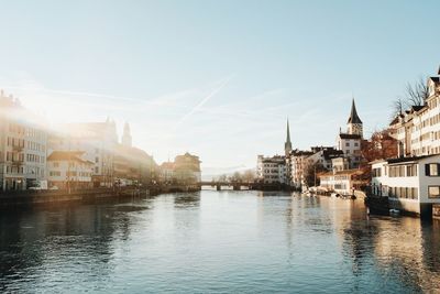 Buildings by river against sky