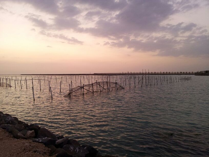 water, sea, tranquil scene, tranquility, sky, scenics, wooden post, beauty in nature, sunset, pier, horizon over water, nature, idyllic, cloud - sky, beach, rippled, reflection, cloud, in a row, wood - material