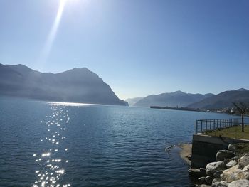 Scenic view of sea and mountains against clear blue sky