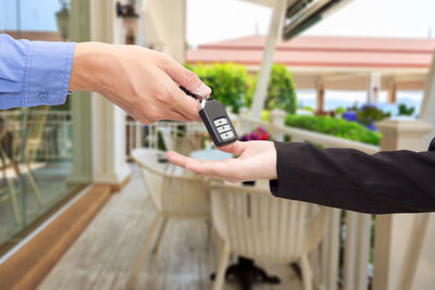 Cropped hand of salesman giving car key to customer outdoors