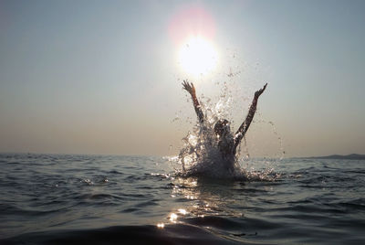 Woman splashing in sea during sunset