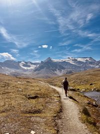 Rear view of man walking on mountain against sky