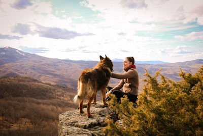 Full length of girl and dog on mountain against sky