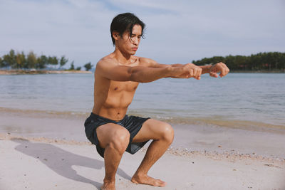 Portrait of shirtless man exercising at beach