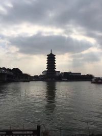 View of city at waterfront against cloudy sky