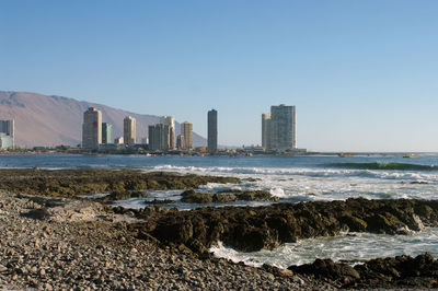 Sea by buildings against clear sky