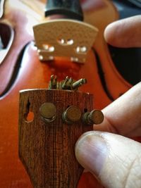 Close-up of the wooden string holder in the hand of a violin maker