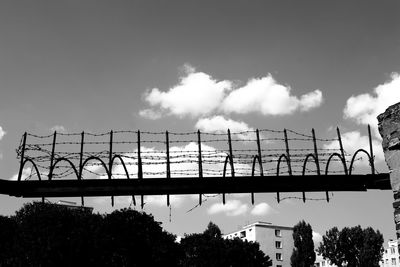 Low angle view of broken fence against cloudy sky