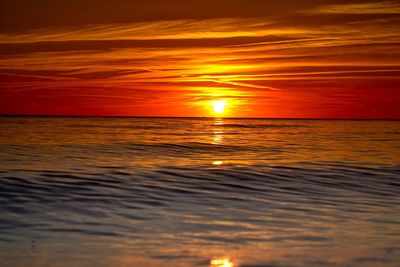 Scenic view of sea against dramatic sky during sunset