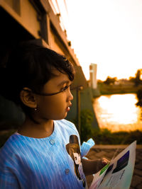 Close-up of thoughtful girl standing against clear sky at sunset