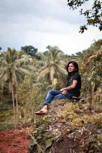 Side view of young woman sitting on rock