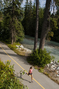 Woman walking on road by trees