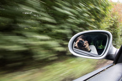 Reflection of man on side-view mirror of car