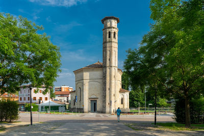 People walking by historic building against sky