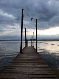 Wooden pier on sea against sky during sunset