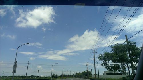 Low angle view of electricity pylon against cloudy sky