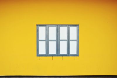 Closed window amidst yellow wall