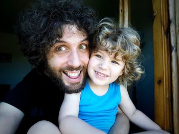 Portrait of cheerful father and son at home