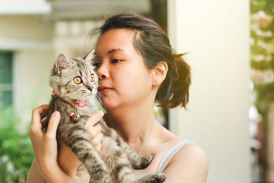 Close-up of woman carrying cat at home