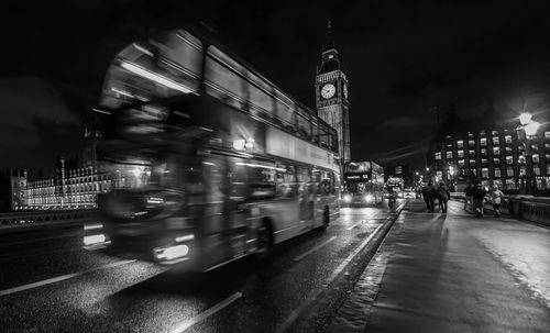 Blurred motion of double-decker bus on westminster bridge in city at night