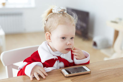 Portrait of cute girl using mobile phone at home