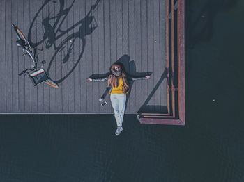 Aerial view of young woman lying on back at edge of coastal jetty