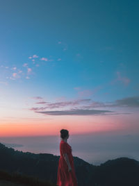 Rear view of man standing against sky during sunset