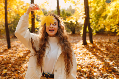 Portrait of young woman standing against trees