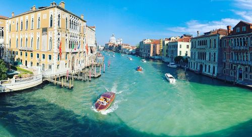 High angle view of boats in canal amidst city against sky