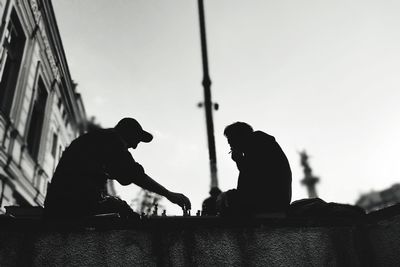 Silhouette men sitting against sky