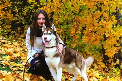 Portrait of young woman with siberian husky on fallen leaves during autumn