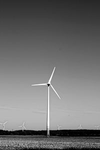 Wind turbines on field against clear sky