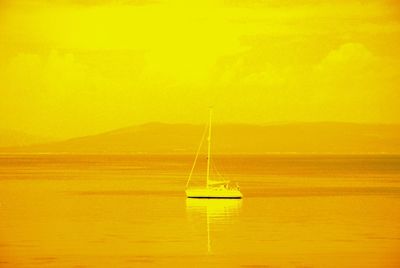 Sailboat sailing on sea against sky during sunset