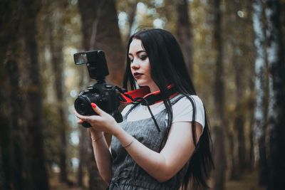 Young woman photographing through camera in forest