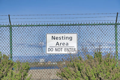 Information sign on fence against clear sky
