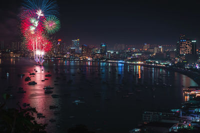 Firework display over river and buildings in city at night