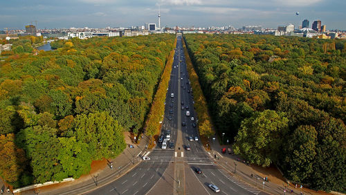 Road amidst trees in city against sky