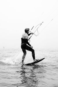 Man jumping on sea against clear sky