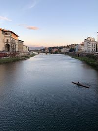 View of river and buildings against sky during sunset