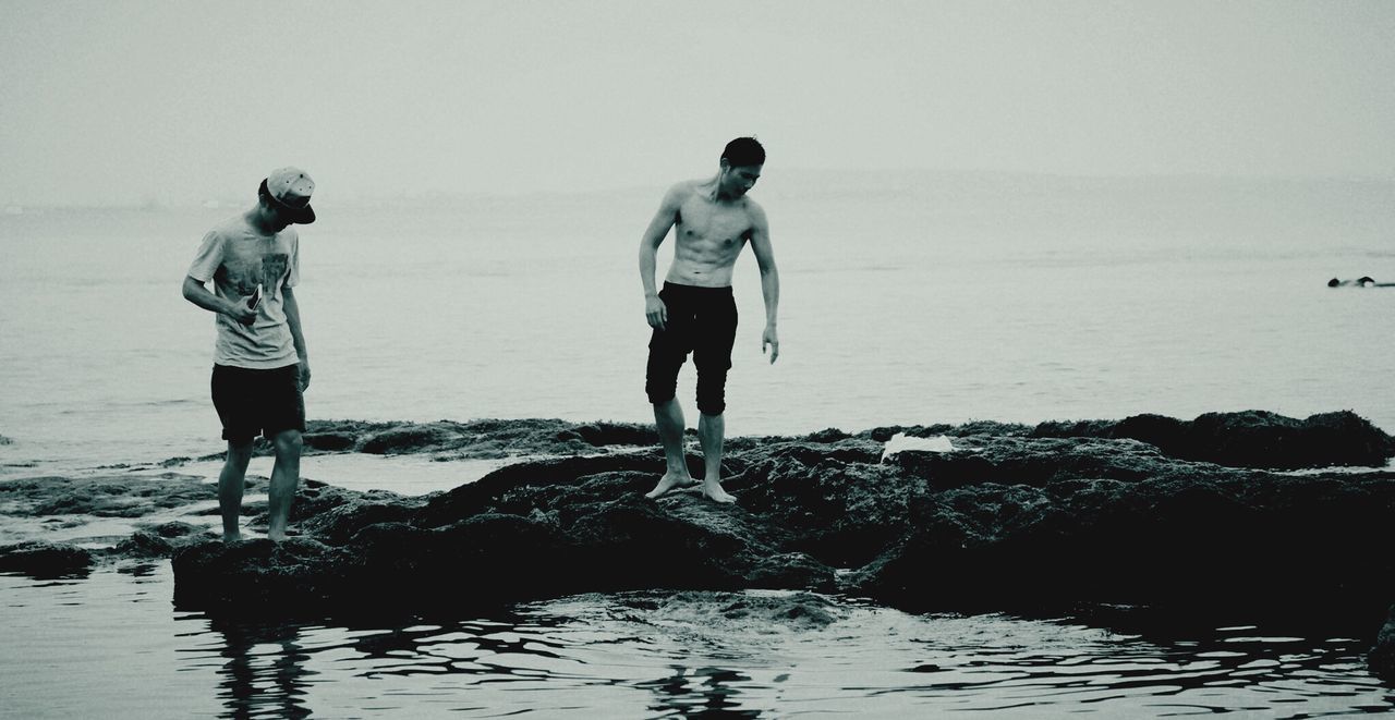 water, sea, full length, horizon over water, lifestyles, clear sky, standing, beach, leisure activity, rear view, men, copy space, shore, nature, scenics, tranquil scene, walking, tranquility