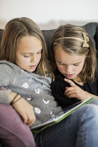 Siblings using digital tablet together on sofa