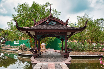 Gazebo in park by lake against sky