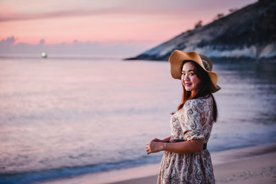 Young woman standing at beach during sunset