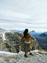 Rear view of man standing on mountain against sky