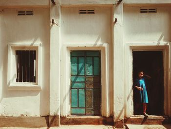 Girl standing on doorway of house