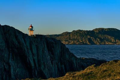 Lighthouse by sea against sky