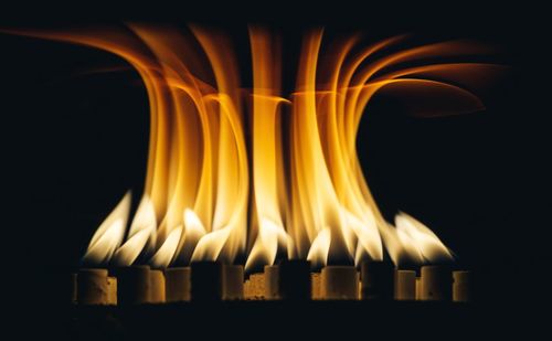 Close-up of burning candles against black background