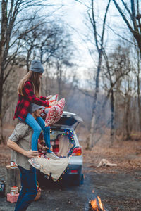 Woman holding umbrella on land against trees