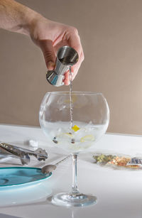 Midsection of person pouring wine in glass on table
